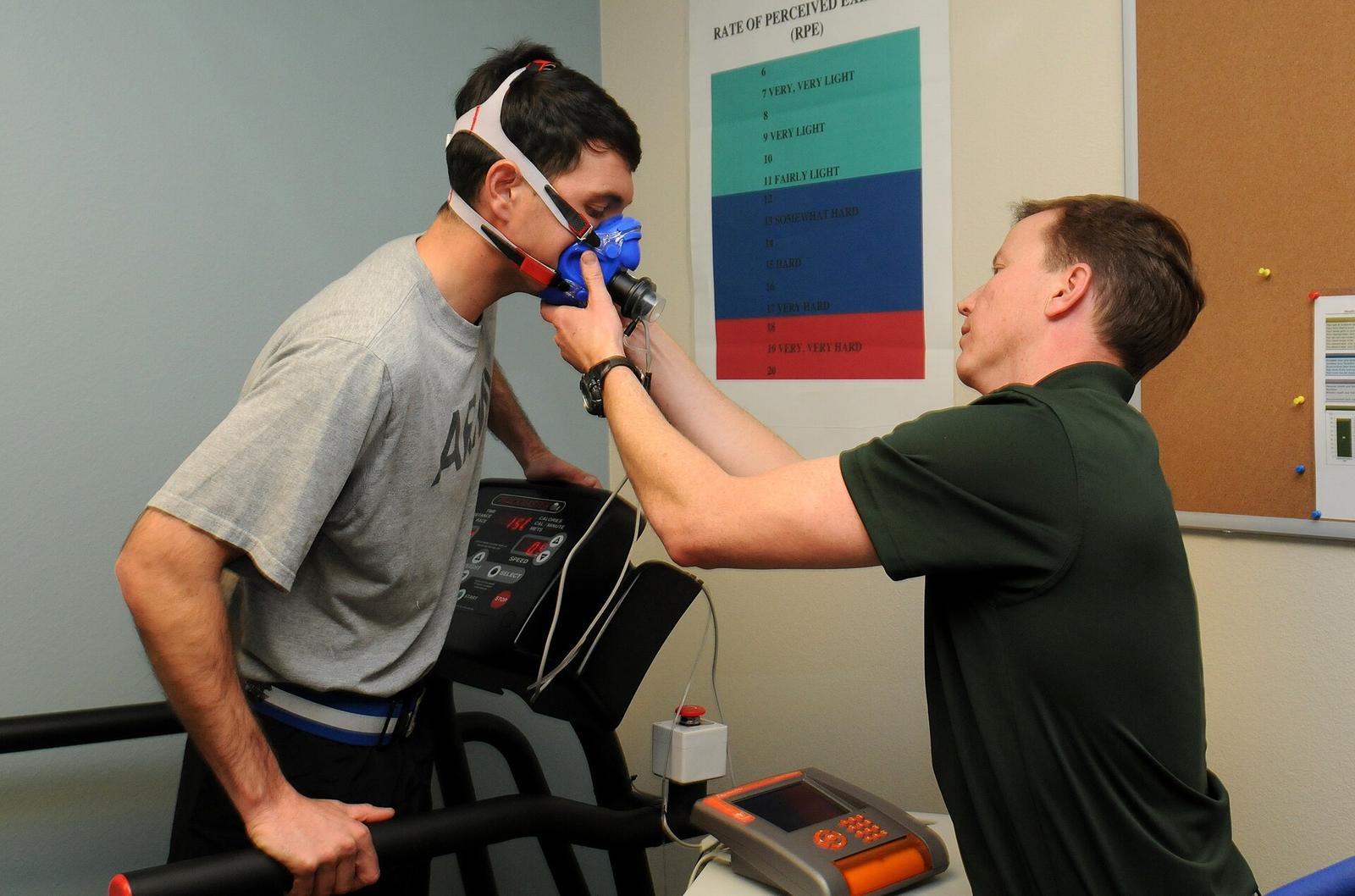A researcher fits a breathing mask on a man on a treadmill during an oxygen-uptake test