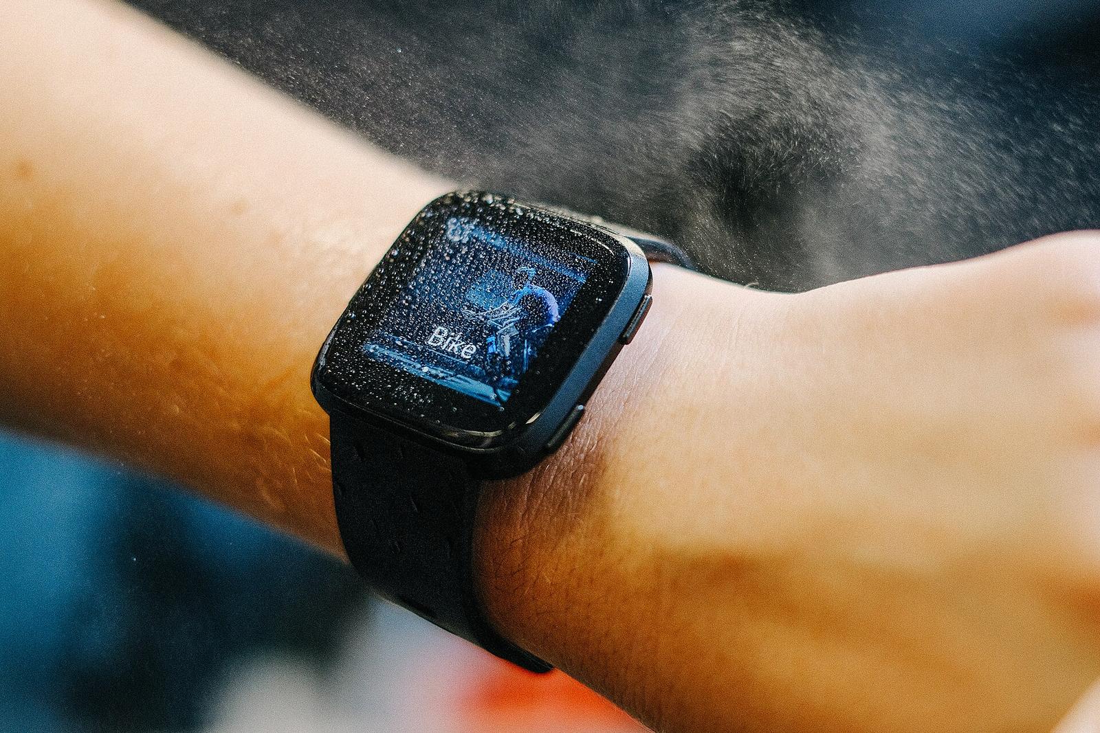 A sweat-spattered fitness smartwatch on a wrist in bike workout mode